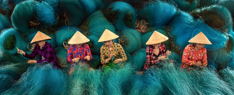 Vietnamese women are sitting repairing fishing nets